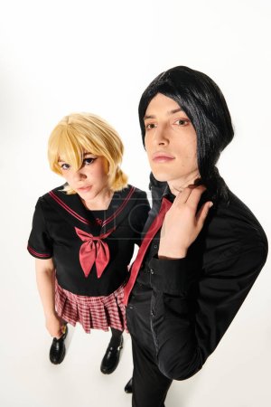 Foto de Amplia vista angular de pareja extravagante en pelucas y uniforme de pie en blanco, concepto de estilo anime - Imagen libre de derechos