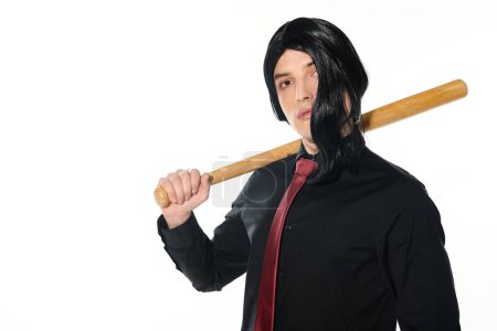 young man in black wig and red tie holding baseball bat and looking at camera on white, cosplayer