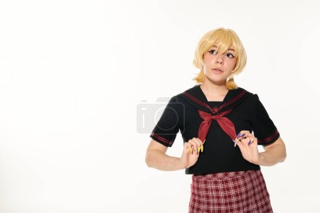 dreamy woman in blonde wig touching red neckerchief and looking away on white, anime style concept