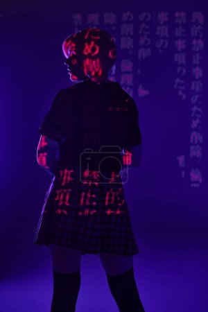 back view of anime woman in school uniform in hieroglyphs projection on blue neon light, subculture