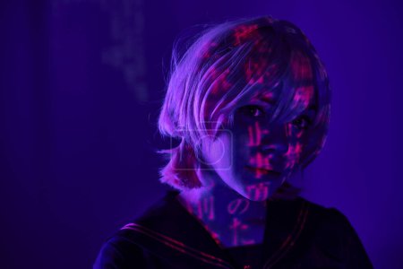 portrait of woman in blonde wig with hieroglyphs projection on blue neon light, anime concept