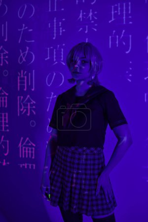 cosplay woman in school uniform standing in blue neon light on backdrop with hieroglyphs projection