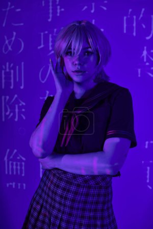 Frau mit blonder Perücke und Schuluniform in blauem Neonlicht mit Hieroglyphen-Projektion, Anime-Trend