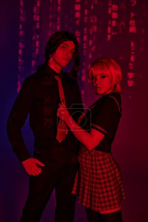 Anime-Paar in Studenten blickt Kamera in rotem Neonlicht auf abstrakt lila Hintergrund