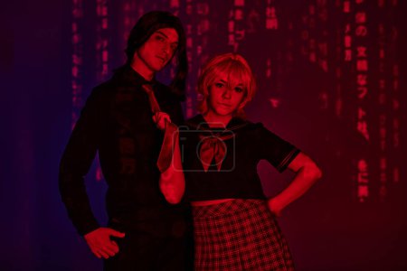 Photo for Anime woman in students uniform pulling tie of man in red neon light on purple abstract backdrop - Royalty Free Image
