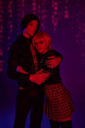 students in wigs and uniform embracing in red neon light on purple abstract backdrop, cosplayers