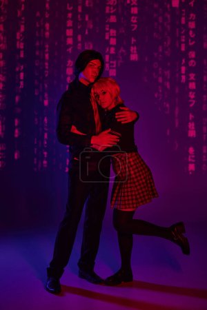 cosplay students in uniform embracing in red neon light on blue and purple abstract backdrop