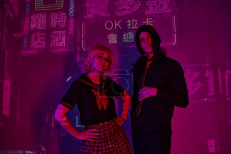 anime woman with hands on hips near trendy man in neon light on purple backdrop with hieroglyphs