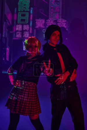 Photo for Anime woman in school uniform showing victory sign near man on purple neon backdrop with hieroglyphs - Royalty Free Image