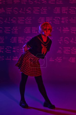 hübsche Frau in Schuluniform posiert auf neonlila Hintergrund mit Hieroglyphen, Anime-Trend