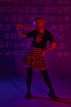 Cosplay-Frau in Schuluniform posiert mit Baseballschläger vor neonviolettem Hintergrund mit Hieroglyphen