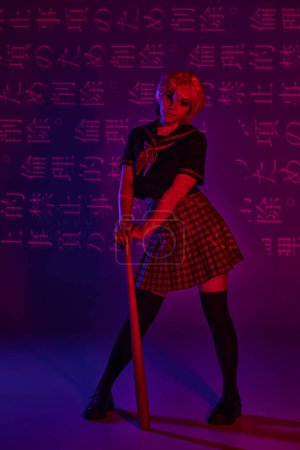Photo for Modern anime woman in school uniform with baseball bat on neon purple backdrop with hieroglyphs - Royalty Free Image