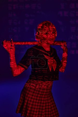 Photo for Anime woman in school uniform with baseball bat in neon light with hieroglyphs on blue backdrop - Royalty Free Image