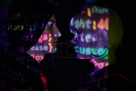 Foto de Vista lateral de los jóvenes estudiantes con letras de programación de neón sobre fondo oscuro, concepto de tendencia de anime - Imagen libre de derechos
