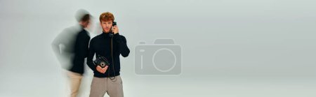 stylish man in elegant turtleneck with landline phone with other man moving, long exposure banner