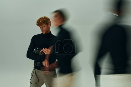 hombre barbudo de pelo rojo con teléfono retro en las manos posando con otros hombres en movimiento, concepto de moda