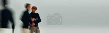 Photo for Bearded man with retro phone in hands posing with other men in motion, fashion concept, banner - Royalty Free Image