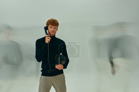 lange verschwommene Belichtung Foto eines jungen Mannes mit Retro-Handy von anderen männlichen Modellen umgeben, Männer Macht