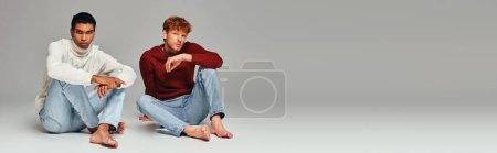 multiracial stylish male models in sweaters sitting on floor looking at camera, men power, banner