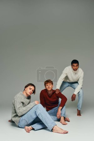 interracial male models in vibrant sweaters posing on gray backdrop, hand on shoulder, men power