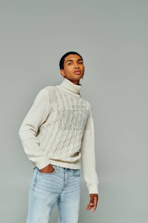ansprechender afrikanisch-amerikanischer Mann mit Accessoires im weißen Pullover, der in die Kamera schaut, Modekonzept