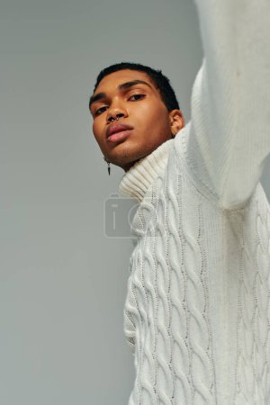 retrato de joven afroamericano guapo en suéter con accesorios mirando a la cámara