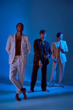 vertical shot of elegant men in classy suits standing and posing with neon lighting on their faces