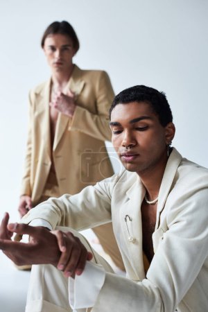 focus on african american man near blurred young man in classy suits, men power, vertical shot