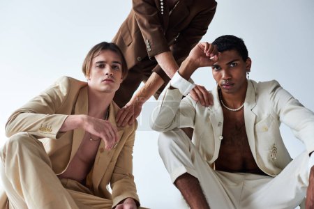cropped view of man in brown suit putting his hand on shoulders of other men, diverse, fashion