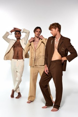 vertical shot of  diverse group of men in vibrant suits with accessories posing on white backdrop
