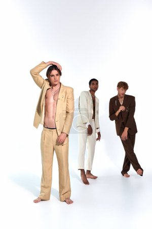 vertical shot of multicultural young men moving relaxedly in vivid classy attires on white backdrop