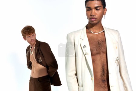 handsome african american man in unbuttoned suit posing with red haired man on backdrop, fashion