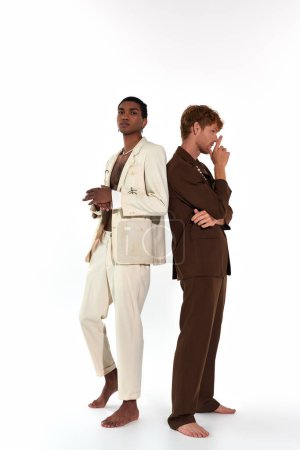 vertical shot of multicultural young male models in elegant suits posing back to back, men power