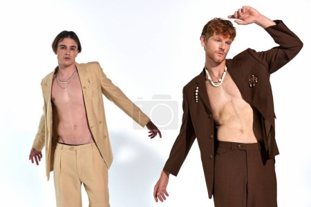 handsome elegant male models in sexy unbuttoned suits posing in motion on white backdrop, fashion