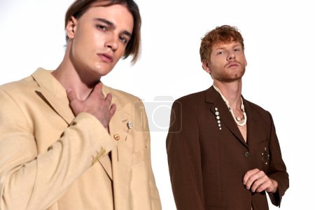 dos atractivos hombres jóvenes en elegantes trajes con clase con accesorios mirando a la cámara, concepto de moda