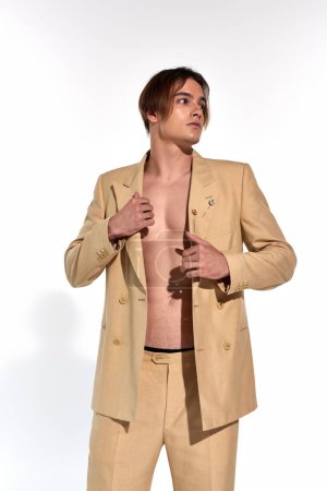 vertical shot of attractive young man in sexy unbuttoned suit posing and looking away, fashion