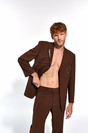 appealing young male model with unbuttoned classy suit with accessories looking at camera, fashion