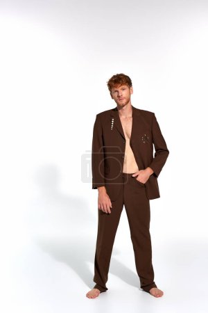 good looking stylish man in brown elegant suit with accessories looking at camera, fashion