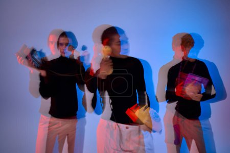 Photo for Good looking young multicultural men with retro phones posing together, neon lights, long exposure - Royalty Free Image