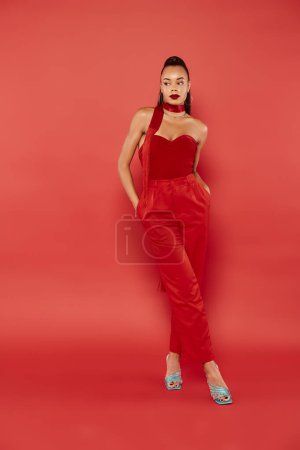 beautiful african american model in red strapless top and pants posing with hands in pockets