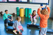 four cheerful children posing on fitness steppers with dumbbells and smiling joyfully, child sport Stickers #677581716