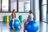 pretty little girls in sportswear sitting on fitness balls and looking at each other, child sport puzzle #677583474