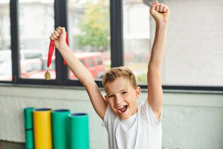 Photo for Joyful preadolescent boy cheering and holding golden metal, smiling happily at camera, child sport - Royalty Free Image