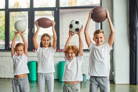 joyeux petits garçons et filles posant avec différents types de boules au-dessus de leurs têtes, sport pour enfants