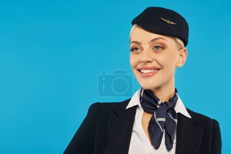 Porträt einer jungen, fröhlichen Frau in eleganter Uniform einer Stewardess, die vor blauem Hintergrund wegschaut