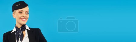 Photo for Portrait of happy young air hostess in stylish corporate uniform smiling on blue background, banner - Royalty Free Image