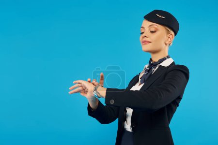 junge elegante Dame in Uniform der Flugbegleiterin, die die Uhrzeit auf der Armbanduhr auf blau überprüft, Pünktlichkeit