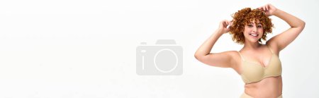 Téléchargez les photos : Positivité du corps, gai modèle rousse courbé posant en sous-vêtements taupe sur blanc, bannière horizontale - en image libre de droit