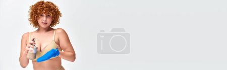 Téléchargez les photos : Rousse femme bouclée en lingerie taupe avec gant de bain et distributeur de savon sur blanc, bannière - en image libre de droit