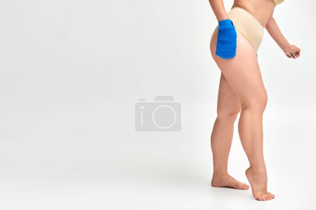 Ausgeschnittene Ansicht einer Plus-Size-Frau, die ihren Körper mit Badehandschuhen auf weiß wäscht, tägliche Routine
